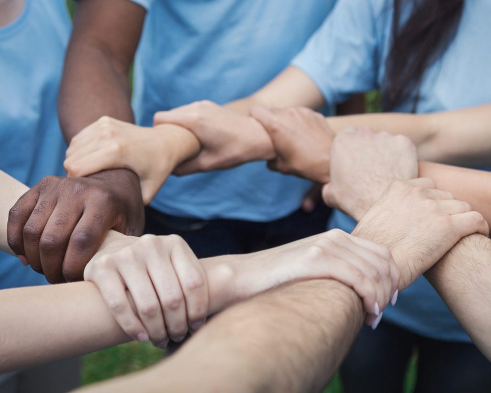 Hands of young people join in circle, making chain, volunteers unite to save the world, copy space